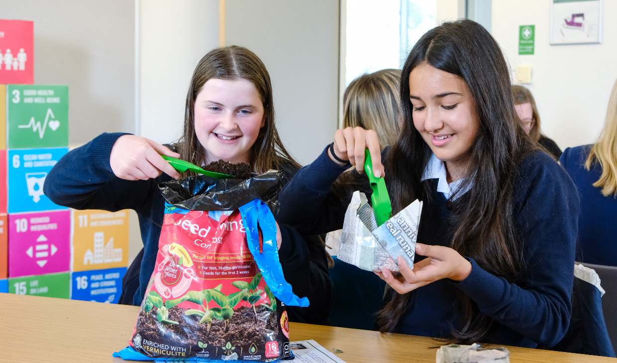 Two school pupils put mud in to paper plant pots at the launch of the Pathfinders initiative