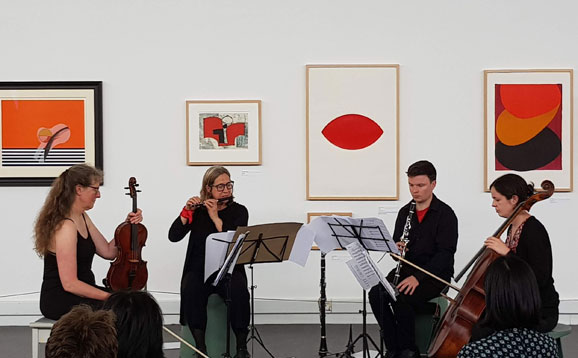 Musicians playing in the Art Collection with artwork displayed on the wall behind them