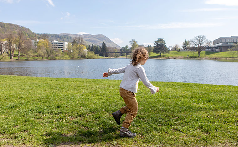 Child running on grass by the loch