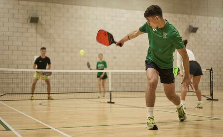 Students playing pickleball in an indoor court